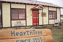 HeartnTreeと丸太に書かれた看板が建物の前にあるカフェandレスト ハートン・ツリーの外観写真